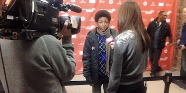 A young performer being interviewed on camera at an event